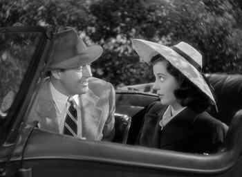 Movie still from “The Uninvited” (1944), directed by Lewis Allen – A man and a woman sitting in the back of a car; Medium shot, High angle