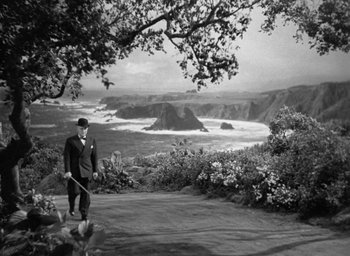 Movie still from “The Uninvited” (1944), directed by Lewis Allen – A black and white photo of a man holding a broom; Extreme Wide shot, High angle