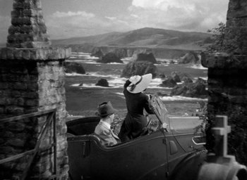 Movie still from “The Uninvited” (1944), directed by Lewis Allen – A man and woman riding in an old fashioned car; Extreme Wide shot, High angle