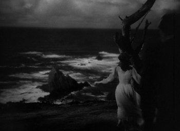Movie still from “The Uninvited” (1944), directed by Lewis Allen – A black and white photo of a woman standing on the beach; Extreme Wide shot, Low angle