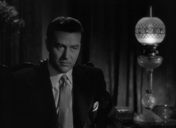 Movie still from “The Uninvited” (1944), directed by Lewis Allen – A black and white photo of a man in a suit and tie; Close Up shot, Low angle