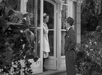 Movie still from “The Uninvited” (1944), directed by Lewis Allen – A man and a woman standing in front of a building; Wide shot, Low angle
