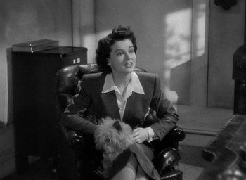 Movie still from “The Uninvited” (1944), directed by Lewis Allen – A woman sitting in a chair holding a dog; Medium shot, High angle