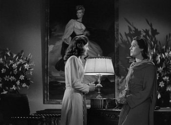 Movie still from “The Uninvited” (1944), directed by Lewis Allen – Two women standing in front of a lamp in front of a painting; Medium shot, Low angle
