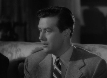 Movie still from “The Uninvited” (1944), directed by Lewis Allen – A man wearing a suit and tie sitting on a couch; Close Up shot, Over the shoulder angle