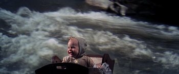Movie still from “The Unsinkable Molly Brown” (1964), directed by Charles Walters – A baby sitting in front of an image of the sky; Medium shot, High angle