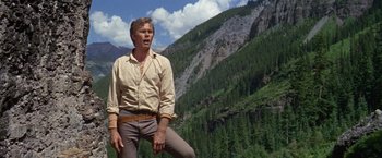 Movie still from “The Unsinkable Molly Brown” (1964), directed by Charles Walters – A man standing in front of a mountain with trees in the background; Medium shot, Low angle