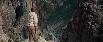 Movie still from “The Unsinkable Molly Brown” (1964), directed by Charles Walters – A man standing on top of a mountain looking down at a river; Wide shot, High angle