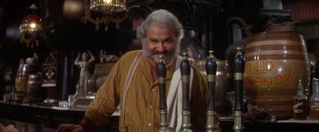 Movie still from “The Unsinkable Molly Brown” (1964), directed by Charles Walters – An older man standing in front of a row of beer taps; Medium shot, Low angle