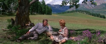 Movie still from “The Unsinkable Molly Brown” (1964), directed by Charles Walters – A man and a woman sitting on the ground in a field; Wide shot, High angle