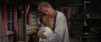 Movie still from “The Unsinkable Molly Brown” (1964), directed by Charles Walters – A man and a woman hugging in a cabin; Medium shot, Low angle