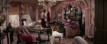 Movie still from “The Unsinkable Molly Brown” (1964), directed by Charles Walters – A man and a woman sitting on a couch in a living room; Wide shot, High angle
