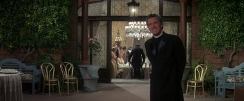Movie still from “The Unsinkable Molly Brown” (1964), directed by Charles Walters – A man in a tuxedo standing in front of a table; Medium shot, Over the shoulder angle