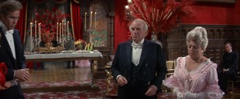 Movie still from “The Unsinkable Molly Brown” (1964), directed by Charles Walters – An older man in a tuxedo standing in a room; Medium shot, Over the shoulder angle