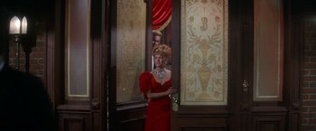 Movie still from “The Unsinkable Molly Brown” (1964), directed by Charles Walters – A woman in a red dress standing in front of a window; Medium shot, Over the shoulder angle