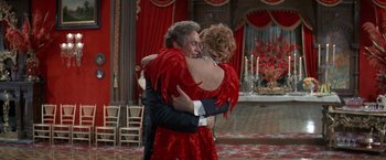 Movie still from “The Unsinkable Molly Brown” (1964), directed by Charles Walters – A man and a woman hugging in a red dress; Medium shot, Over the shoulder angle