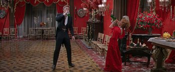 Movie still from “The Unsinkable Molly Brown” (1964), directed by Charles Walters – A man and a woman in formal wear holding wine glasses; Wide shot, Low angle