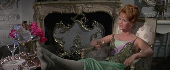 Movie still from “The Unsinkable Molly Brown” (1964), directed by Charles Walters – A woman sitting on a couch holding a glass of wine; Medium shot, High angle