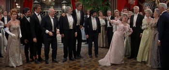 Movie still from “The Unsinkable Molly Brown” (1964), directed by Charles Walters – A group of men and women in formal attire; Wide shot, Over the shoulder angle