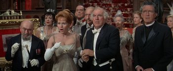 Movie still from “The Unsinkable Molly Brown” (1964), directed by Charles Walters – A group of people standing around each other in formal wear; Medium shot, High angle