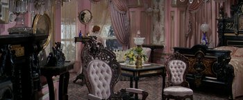 Movie still from “The Unsinkable Molly Brown” (1964), directed by Charles Walters – A room filled with furniture and a table with flowers on it; Wide shot, High angle