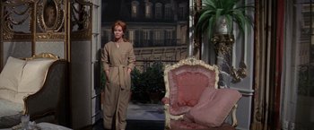 Movie still from “The Unsinkable Molly Brown” (1964), directed by Charles Walters – A woman standing in front of a chair in a living room; Wide shot, Low angle