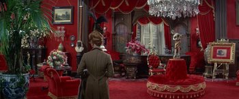 Movie still from “The Unsinkable Molly Brown” (1964), directed by Charles Walters – A woman standing in front of a living room with red walls; Wide shot, High angle