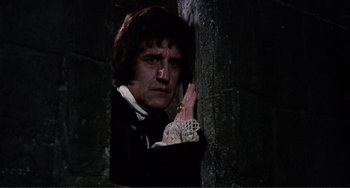 Movie still from “The Vampire Lovers” (1970), directed by Roy Ward Baker – A man in a black shirt and a white lace shirt; Medium shot, Low angle