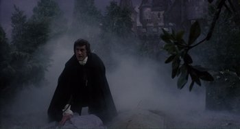 Movie still from “The Vampire Lovers” (1970), directed by Roy Ward Baker – A man standing next to a dead body in the fog; Wide shot, Low angle