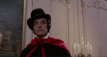 Movie still from “The Vampire Lovers” (1970), directed by Roy Ward Baker – A man wearing a red cape and a black hat; Medium shot, Low angle