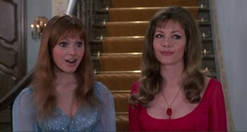 Two women standing next to each other in front of a staircase