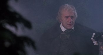 Movie still from “The Vampire Lovers” (1970), directed by Roy Ward Baker – An older man in a black jacket and a white beard; Medium shot, Low angle