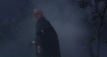 Movie still from “The Vampire Lovers” (1970), directed by Roy Ward Baker – An old man in a long black coat standing in the fog; Medium shot, Low angle