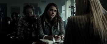 Movie still from “The Veil” (2016), directed by Phil Joanou – A woman sitting at a table in front of a camera; Medium shot, Over the shoulder angle