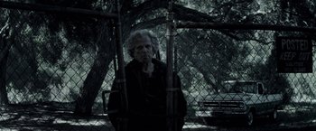 Movie still from “The Veil” (2016), directed by Phil Joanou – An old man standing next to a tree; Medium shot, Over the shoulder angle