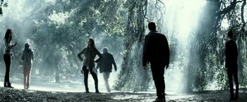 Movie still from “The Veil” (2016), directed by Phil Joanou – A group of people standing in the woods near a tree; Wide shot, Low angle