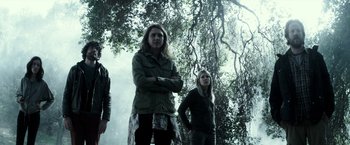 Movie still from “The Veil” (2016), directed by Phil Joanou – A group of people standing next to each other under a tree; Medium shot, Low angle