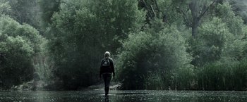 Movie still from “The Veil” (2016), directed by Phil Joanou – A person with a back pack walking in the rain; Wide shot, Low angle