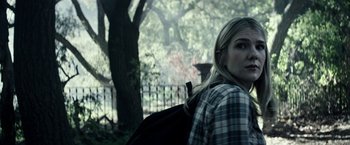 Movie still from “The Veil” (2016), directed by Phil Joanou – A woman in a plaid shirt is standing in front of a tree; Close Up shot, Over the shoulder angle