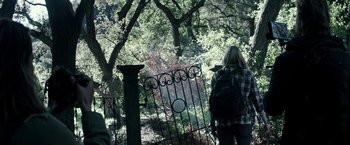 Movie still from “The Veil” (2016), directed by Phil Joanou – A woman with a backpack standing at the gate of a garden; Wide shot, Over the shoulder angle