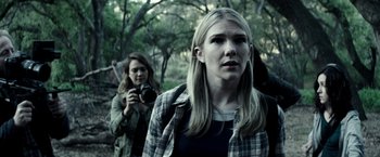Movie still from “The Veil” (2016), directed by Phil Joanou – Two women are walking in the woods with a camera in hand; Close Up shot, Over the shoulder angle