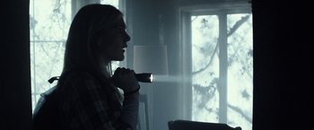 Movie still from “The Veil” (2016), directed by Phil Joanou – A woman holding a flashlight in front of a window; Medium shot, Over the shoulder angle