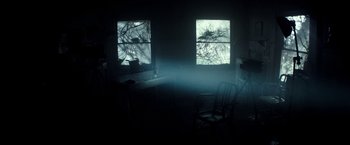 Movie still from “The Veil” (2016), directed by Phil Joanou – A dark room with two windows and a chair; Wide shot, High angle