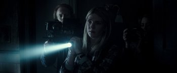 Movie still from “The Veil” (2016), directed by Phil Joanou – A woman holding a flashlight in a dark room; Medium shot, Over the shoulder angle