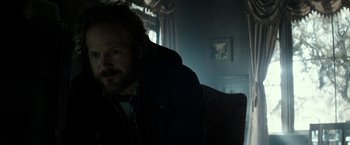 Movie still from “The Veil” (2016), directed by Phil Joanou – A man sitting in a chair in front of a painting; Close Up shot, Over the shoulder angle