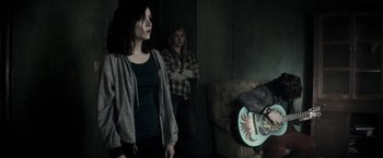 Movie still from “The Veil” (2016), directed by Phil Joanou – A group of people standing in a living room; Medium shot, Over the shoulder angle