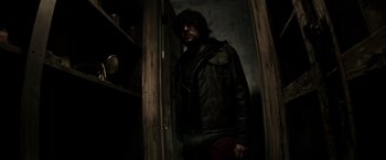 Movie still from “The Veil” (2016), directed by Phil Joanou – A man standing in front of an open door in a dark room; Medium shot, Low angle