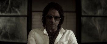 Movie still from “The Veil” (2016), directed by Phil Joanou – A man with long black hair wearing sunglasses; Close Up shot, Low angle