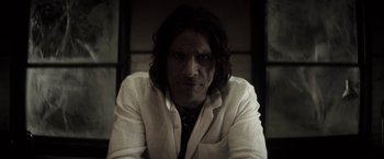 Movie still from “The Veil” (2016), directed by Phil Joanou – A man with long black hair wearing a white jacket; Close Up shot, Low angle
