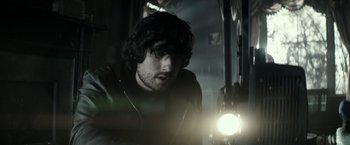 Movie still from “The Veil” (2016), directed by Phil Joanou – A man with a beard is looking at a light; Close Up shot, Over the shoulder angle